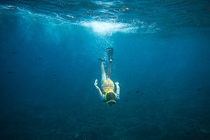 underwater photo of woman in fins, diving mask and snorkel diving alone in ocean