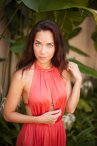 attractive young woman in dress in front of tropical plants