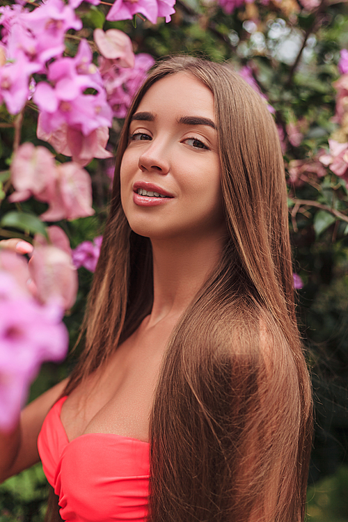 portrait of beautiful young girl posing at pink flowers