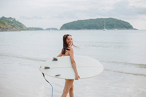 beautiful surfer holding surfboard and going into ocean