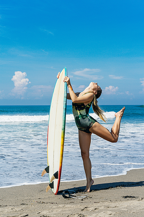 young female surfer posing with surfboard at the sea