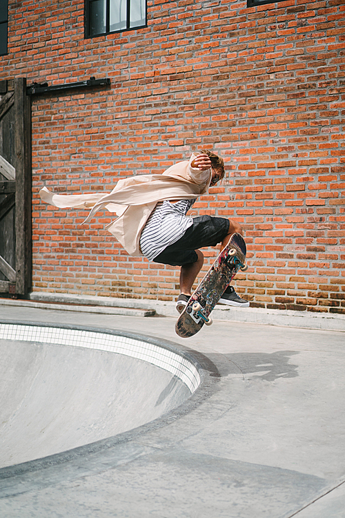 handsome skater jumping from pool in skatepark