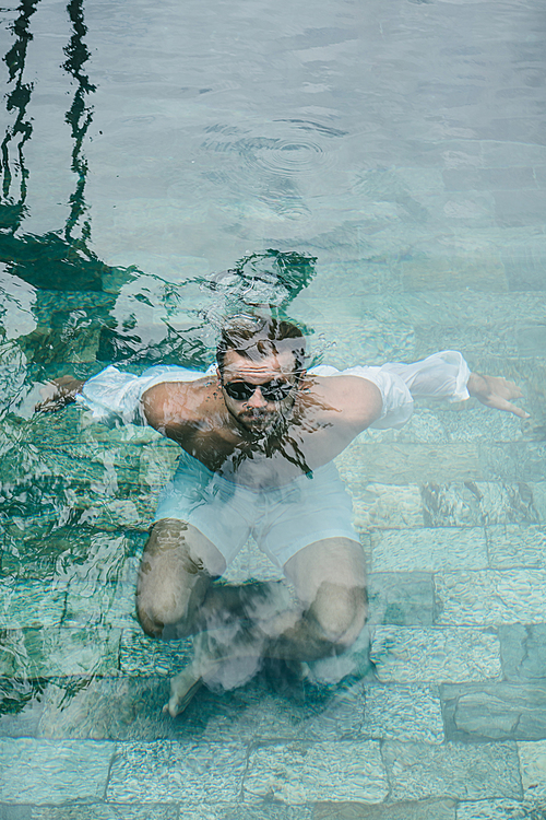 man in sunglasses under water in swimming pool in Bali, Indonesia