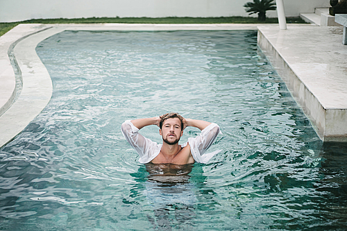 seductive handsome man in swimming pool in Bali, Indonesia