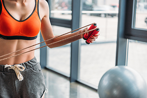 cropped shot of sportswoman holding jump rope at gym