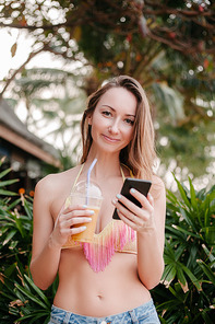 attractive woman using smartphone and holding cocktail