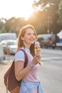 young happy woman with backpack holding ice cream