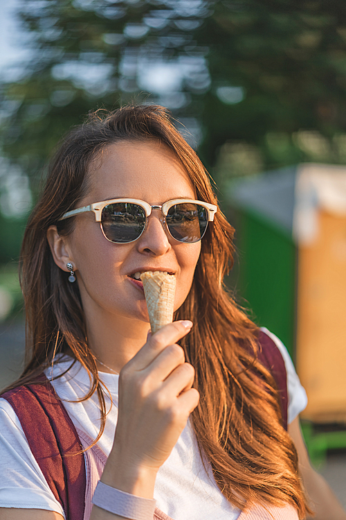 smiling young woman in sunglasses eating ice cream