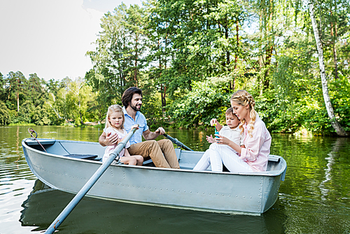 happy young family riding boat on river at park