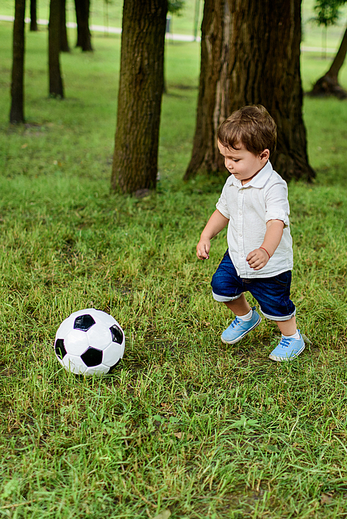 adorable little kid playing with football ball in park
