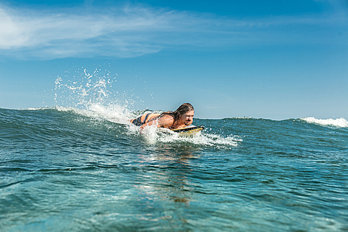 male athlete swimming on surfing board in ocean at Nusa Dua Beach, Bali, Indonesia