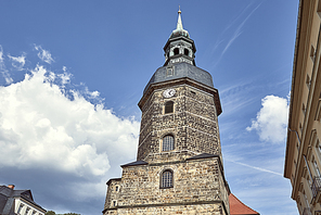 low angle view of old historical church of St John with clock against blue sky in Bad Schandau, Germany