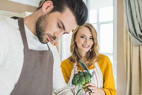 Young loving couple preparing vegetables in modern kitchen