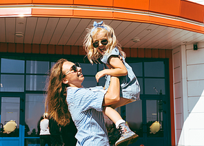 happy stylish mother holding her adorable daughter in hands