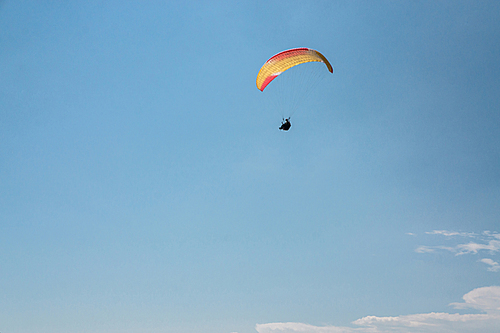 man flying on paraglider, blue sky on background