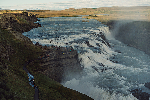 group of tourists looking at majestic waterfall in Iceland