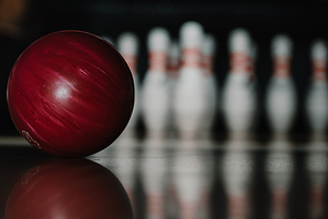 close-up shot of red bowling ball on alley in front of pins