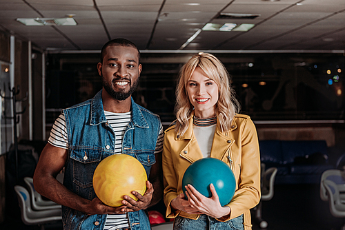 young couple with bowling balls  at club