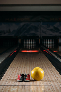 yellow bowling ball with rental shoes on alley at club