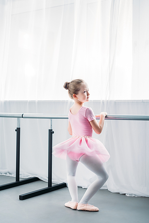 back view of adorable little ballerina exercising in ballet school