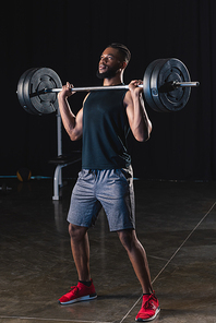 athletic african american man in sportswear lifting barbell in gym