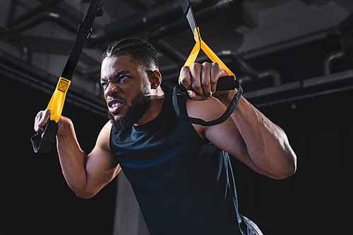 low angle view of muscular african american sportsman training with fitness straps