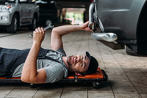 mechanic lying and working under car in auto repair shop