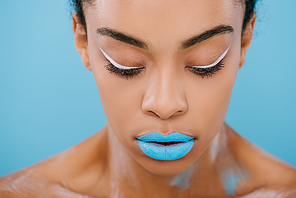 close-up portrait of african american woman with creative makeup and perfect skin isolated on blue
