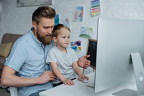 유토이미지 | father and little son looking at computer screen while using ...