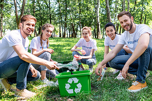 young volunteers with green recycling box cleaning park