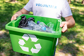 cropped view of volunteer holding recycling box with plastic trash
