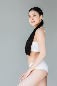 attractive asian woman in white lingerie posing on gray background