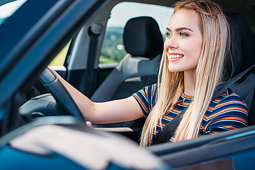 close up shot of smiling young woman driving car