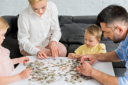 cropped shot of happy family playing with puzzle pieces at home