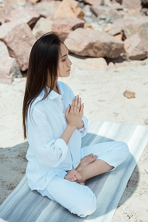 high angle view of focused asian woman meditating with closed eyes in anjali mudra rT6y_vb! pose on yoga mat