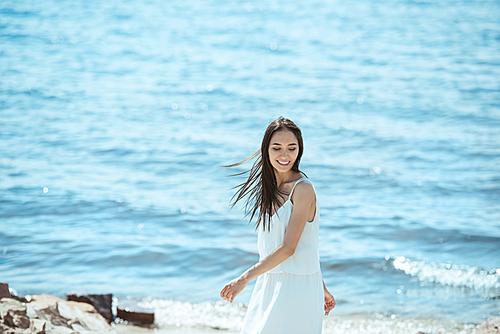 smiling asian woman in white dress standing by sea during daytime
