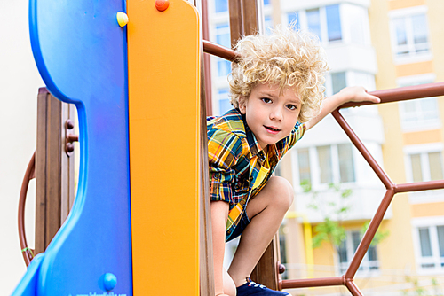 selective focus of adorable curly little boy having fun at playground