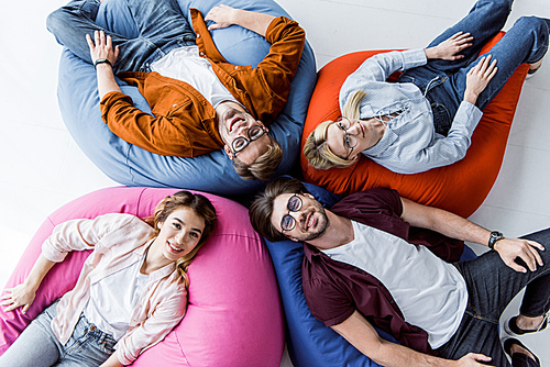 top view multicultural colleagues of startup project lying on bean bag chairs in office