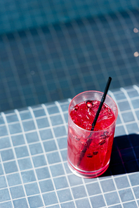 close-up shot of glass of delicious berry cocktail on poolside