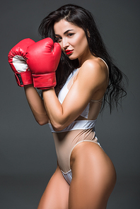 side view of sexy sportive woman in white sportswear and boxing gloves  isolated on grey