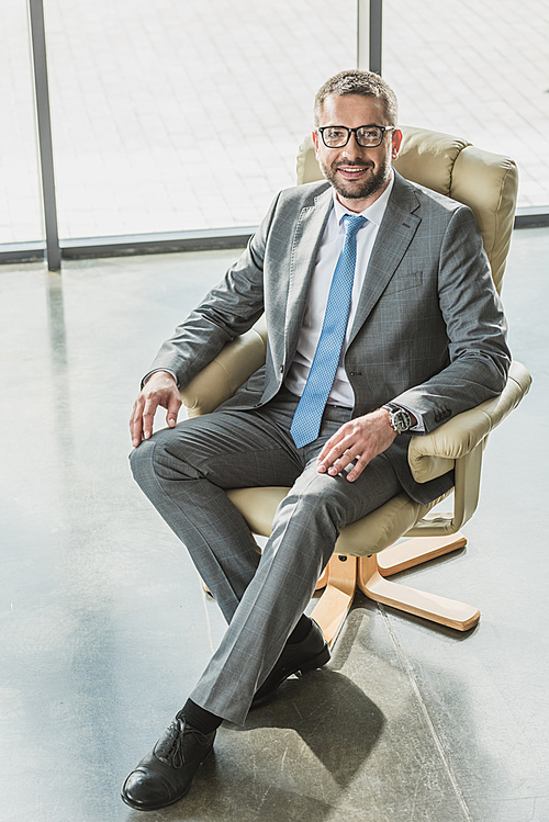 high angle view of handsome happy businessman sitting on luxury armchair and  at modern office
