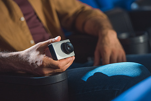 partial view of man with small video camera illegally filming movie in cinema