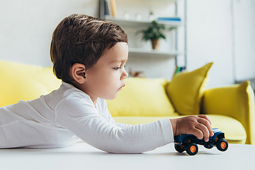 adorable little boy playing with toy car at home