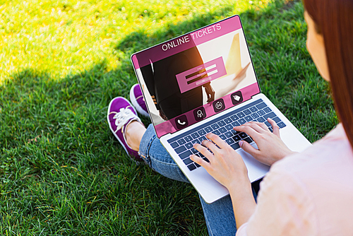 cropped image of woman using laptop with online tickets appliance in park