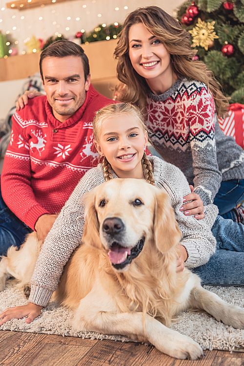 happy parents and daughter with golden retriever dog near christmas tree