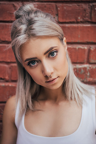 portrait of beautiful blonde girl standing near brick wall and 