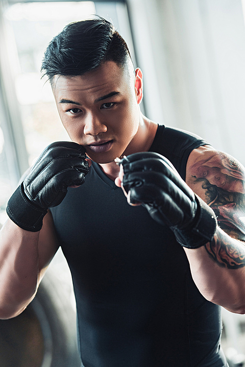 young asain sportsman wearing black boxing gloves