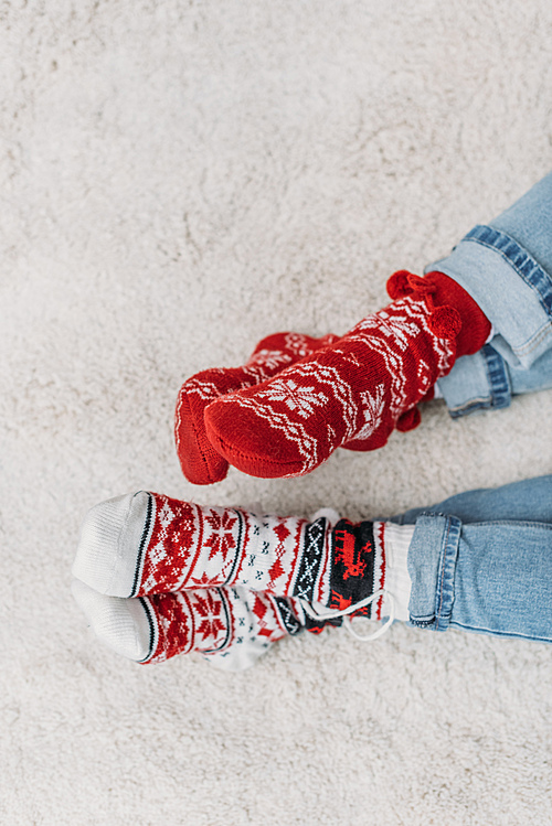 cropped image couple sitting on carpet in jeans and red christmas socks