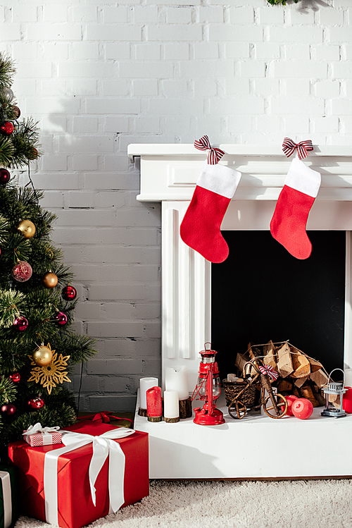 christmas tree with baubles, gift boxes and fireplace with christmas stockings at home