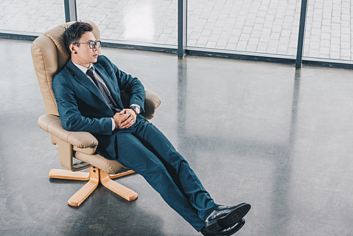 high angle view of young businessman in suit sitting in chair at workplace